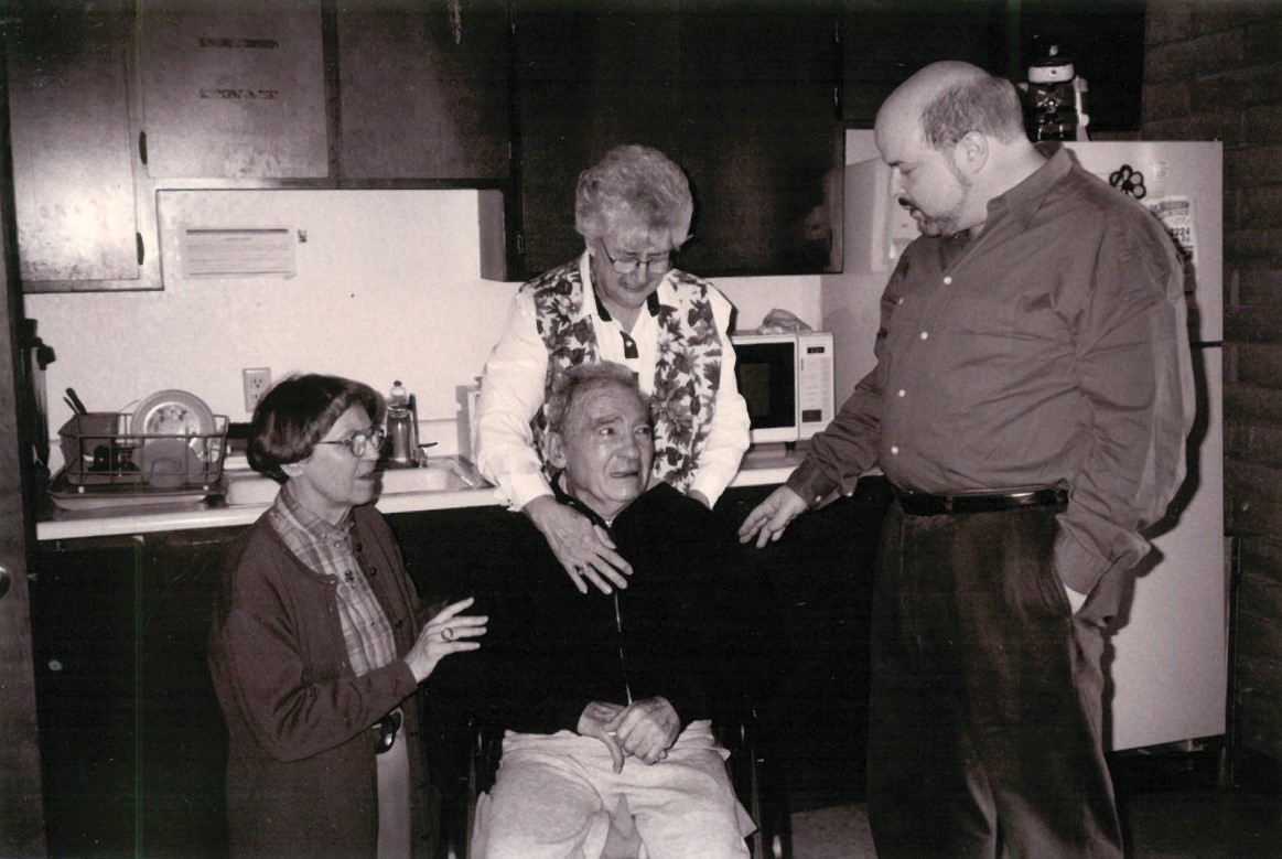 3 After his stroke, Louis Kaplan would sometimes visit the offices of Jewish Voice Broadcasts, the ministry he founded and loved. Here, circa June 1997, Chira, Maddy Lindvall (friend, staff, and JVB board member), and Jonathan Bernis join staff gathered in the breakroom to pray for Louis.