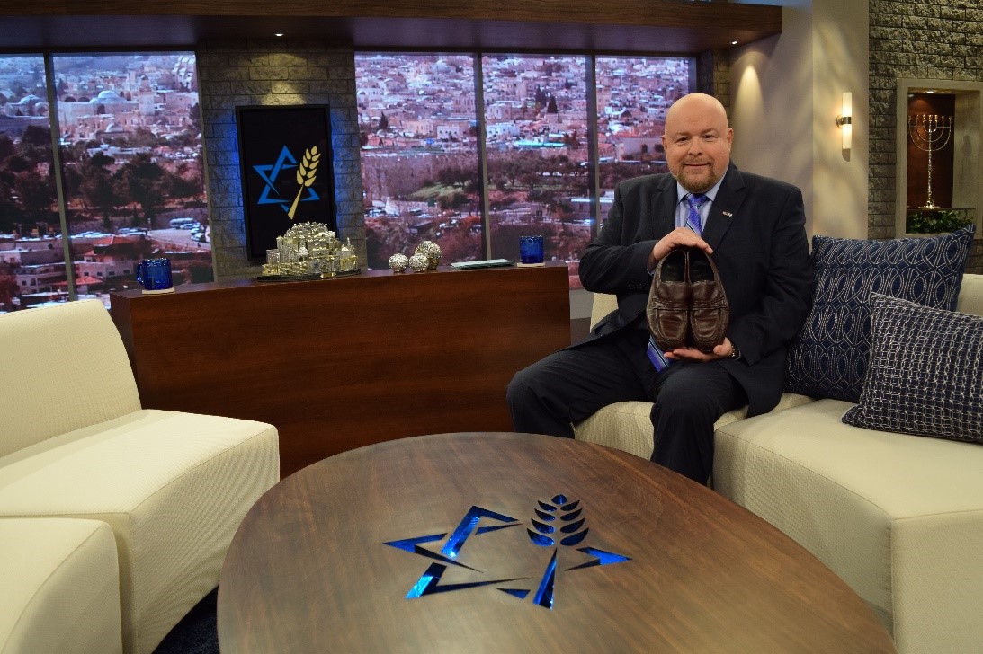  Jonathan Bernis holds a pair of shoes belonging to the late Louis Kaplan. When Jonathan questioned whether he could fill Louis’ ministry shoes, Chira Kaplan presented him with three pairs of new shoes Louis had bought but never worn before he passed away. They were Jonathan’s exact, and unusual, shoe size.